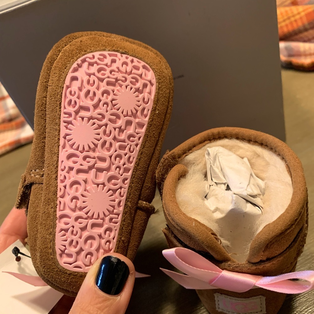 Brand new, never worn Ugg Infant size 0/1 (0-6months). Chestnut/pink bows